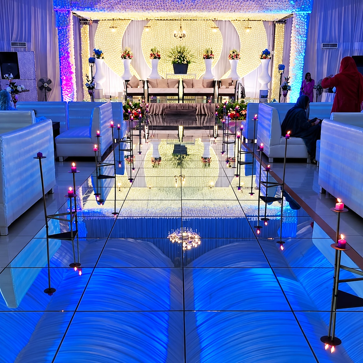 Reception stage with blue-lit mirror walkway and candle stands